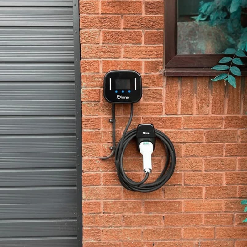 Ohme Home Pro EV charger installed on a brick wall with the cable coiled